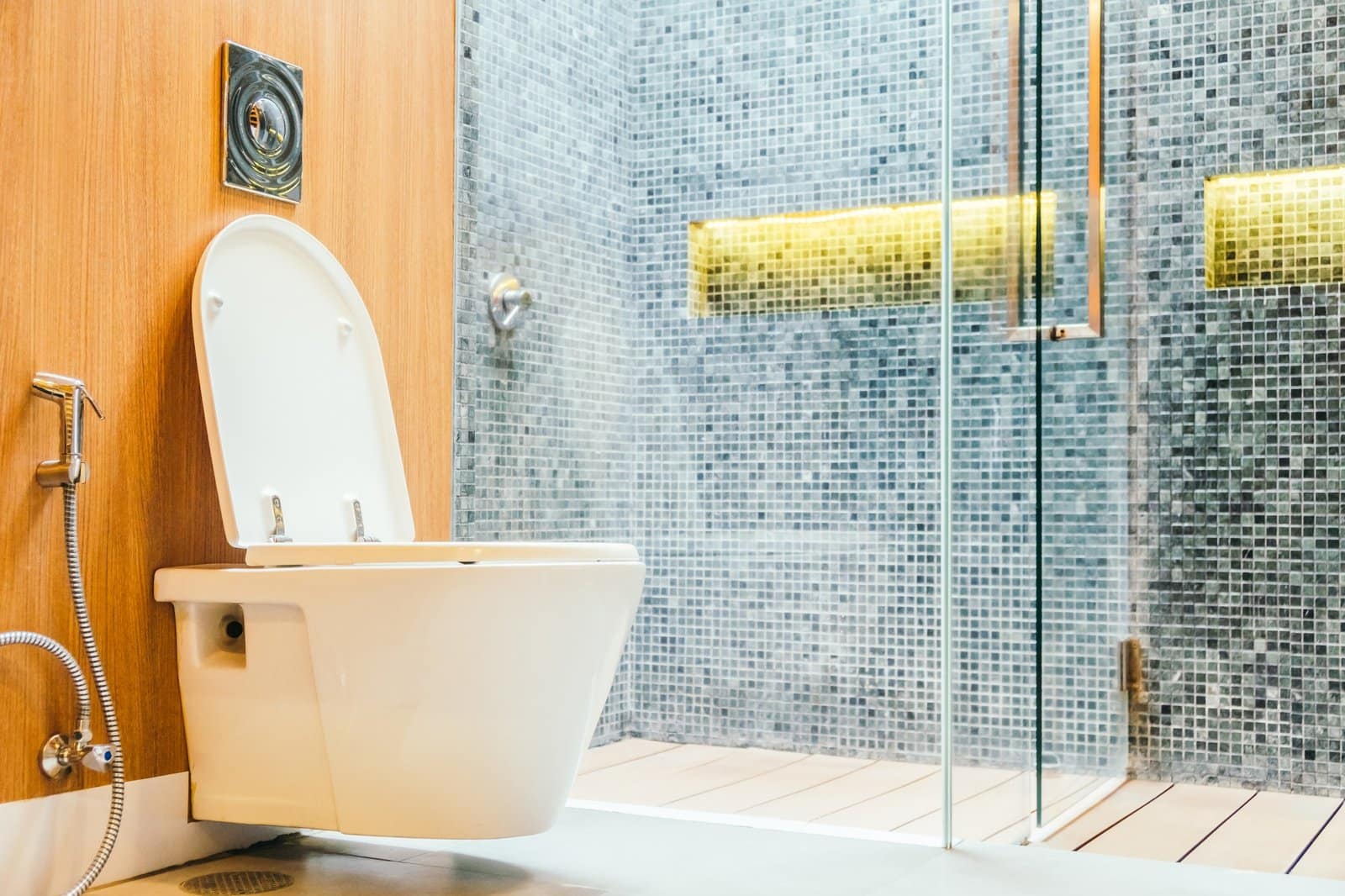 Bagno con wc sospeso, doccia a filo pavimento e rivestimento a mosaico