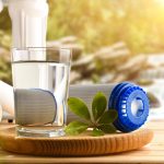 bicchiere d'acqua accanto a dei filtri di depurazione