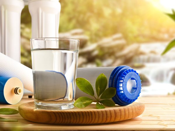 bicchiere d'acqua accanto a dei filtri di depurazione